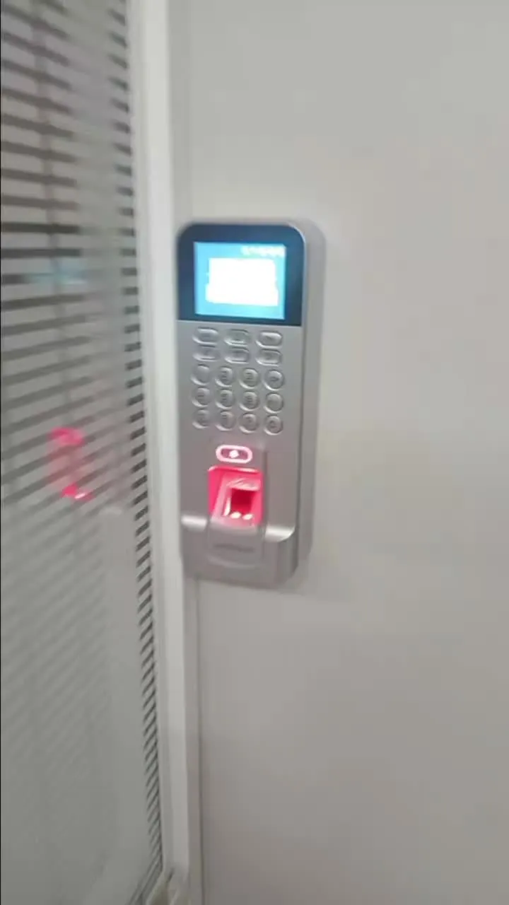 Fingerprint and keypad access control reader beside a glass office door