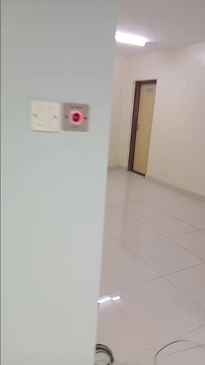 Infrared no-touch exit button mounted beside a light switch in an office corridor