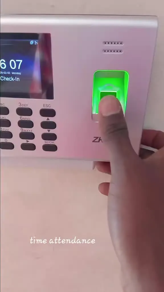 Employee pressing a finger on a ZKTeco fingerprint attendance terminal showing Check-In