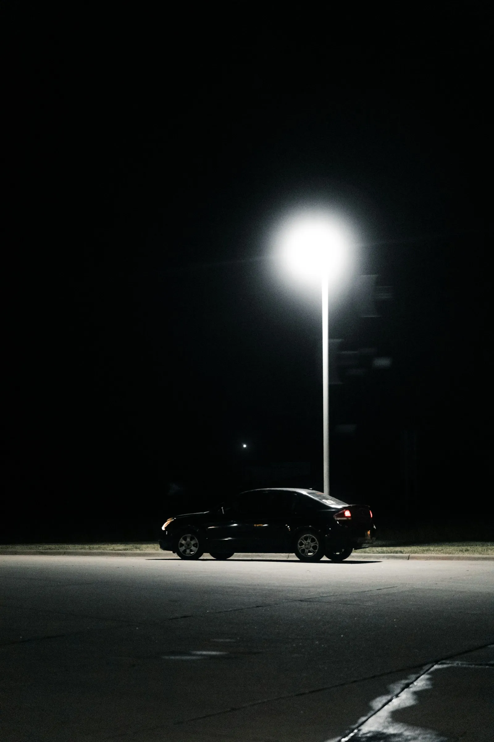 Car parked alone under a street light at night